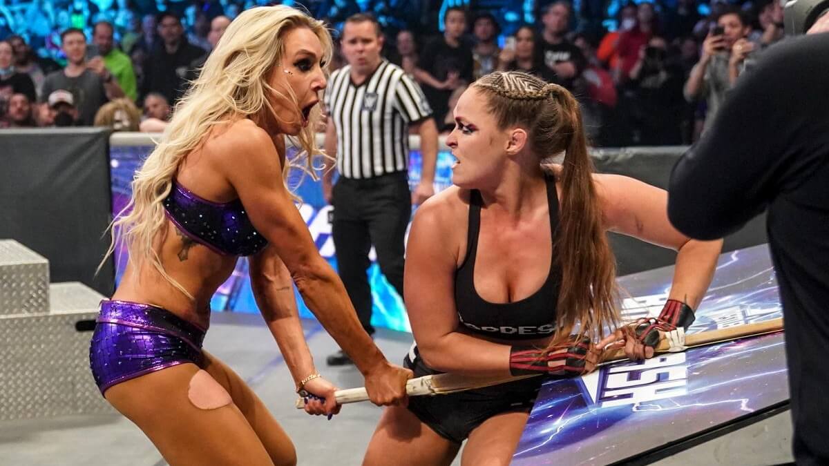 Charlotte Flair and Ronda Rousey fighting over a kendo stick