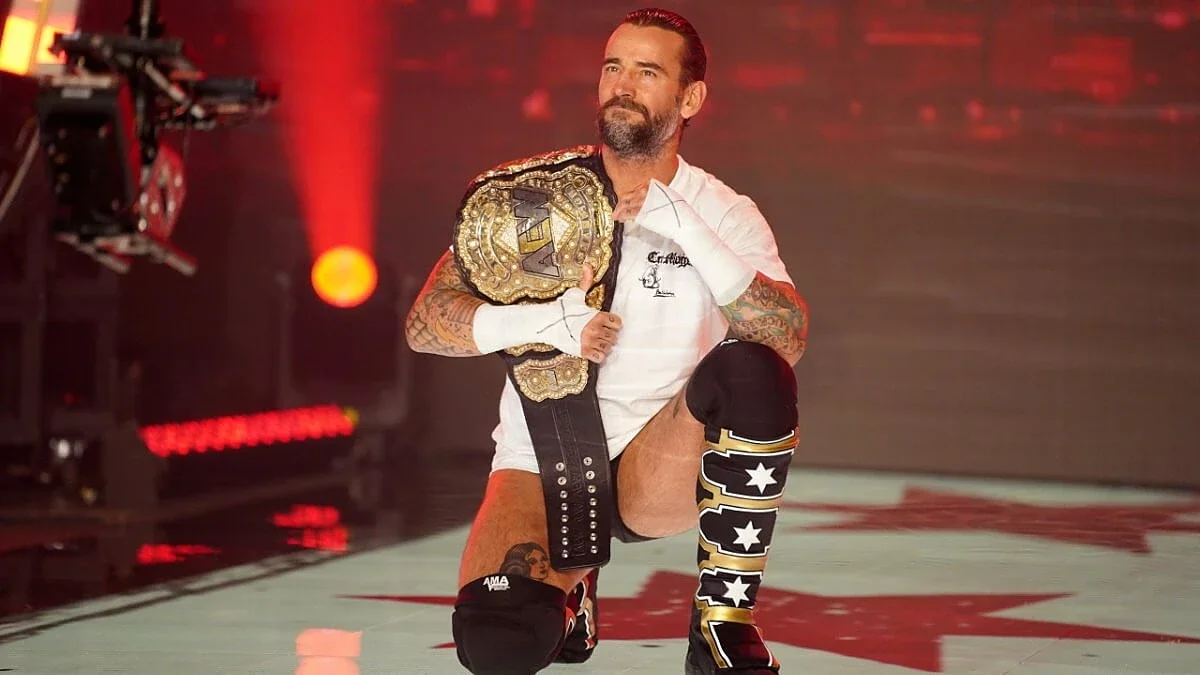 CM Punk kneeling with AEW World Championship.