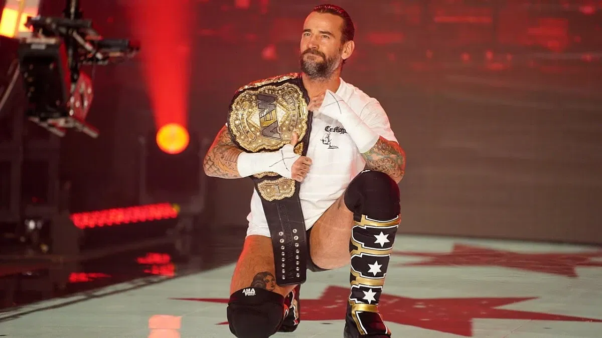 CM Punk kneeling with AEW World Championship.