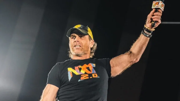 Shawn Michaels in the ring at an NXT live event holding the microphone in the air