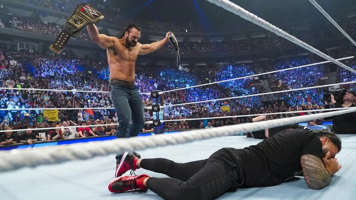 Drew McIntyre standing over Roman Reigns with the Undisputed WWE Universal Championship