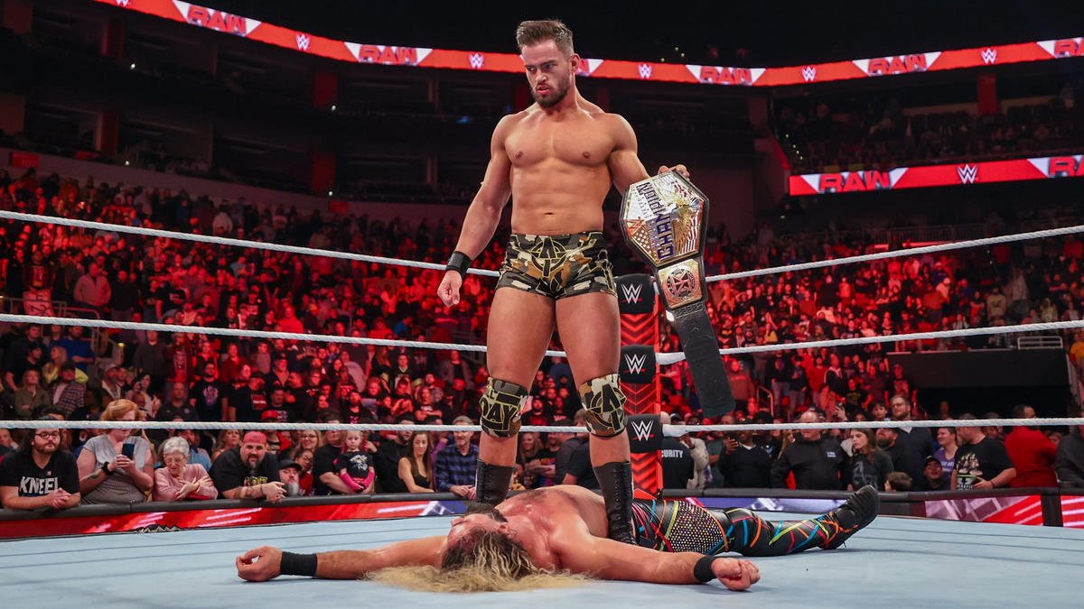 Austin Theory stands tall over Seth Rollins with the United States Championship