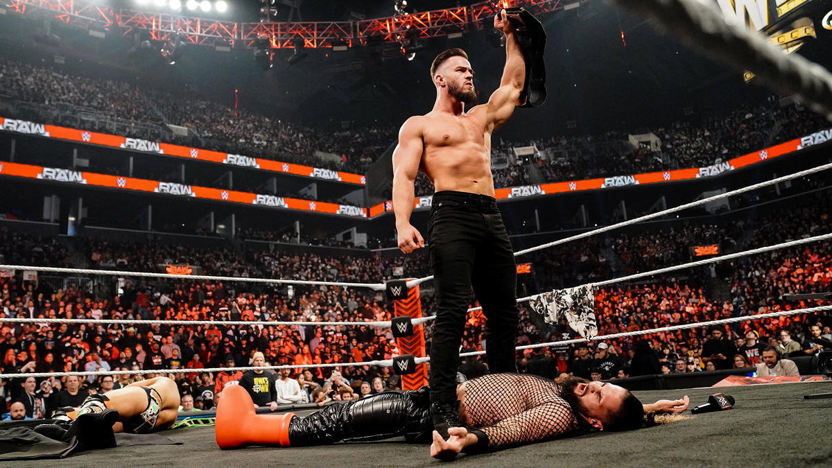 WWE star Austin Theory standing over Seth Rollins