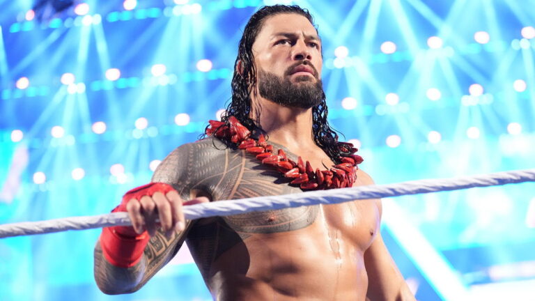 WWE star Roman Reigns holding the ring rope wearing the Ula Fala lei