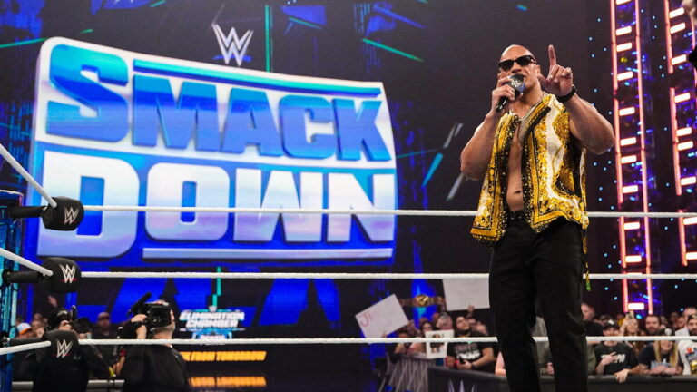 The Rock in the ring with a WWE SmackDown logo on the Titantron screen in the background