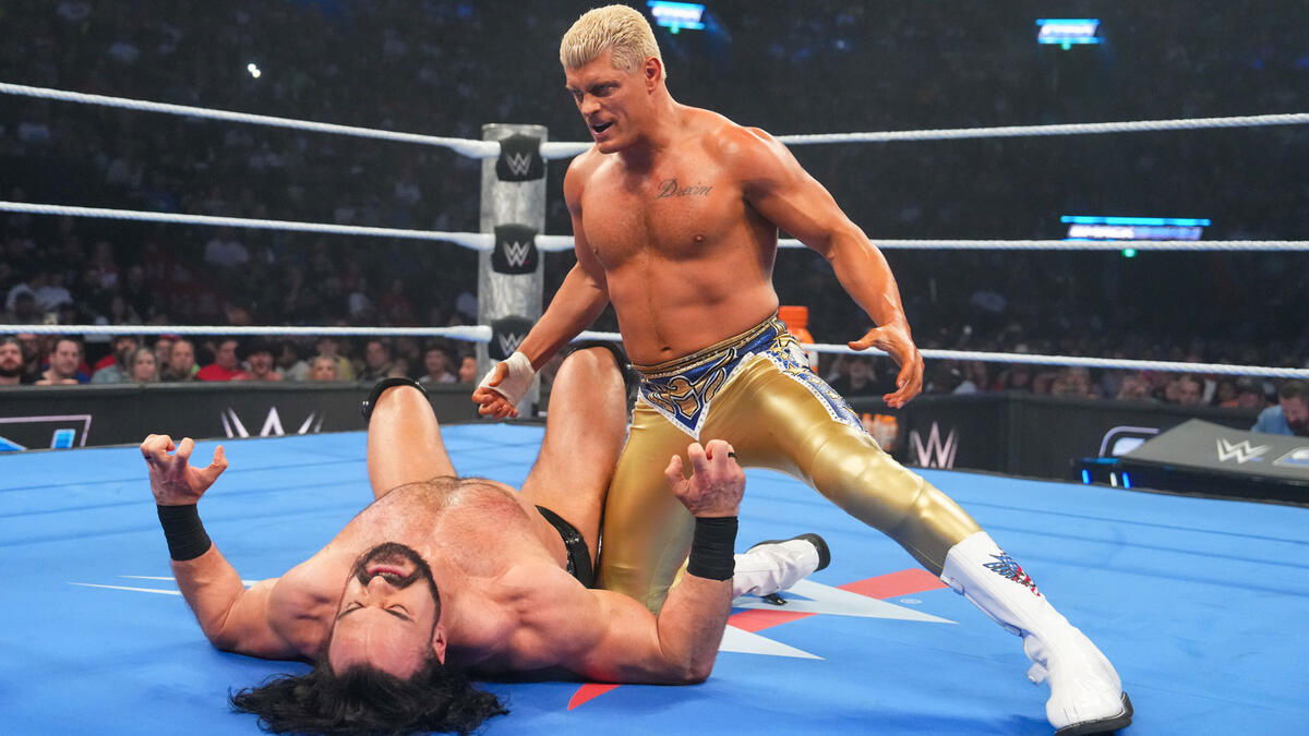 WWE star Cody Rhodes kneeling over Drew McIntyre